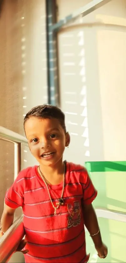 Child smiling in striped red shirt under sunlight.