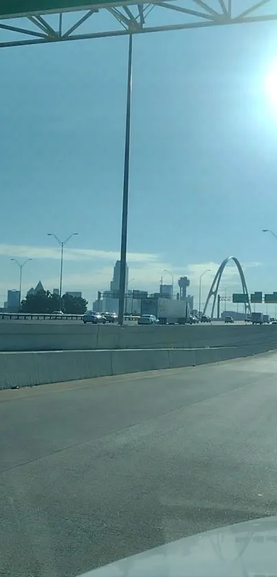 City road with skyline and iconic arch under sunny sky.