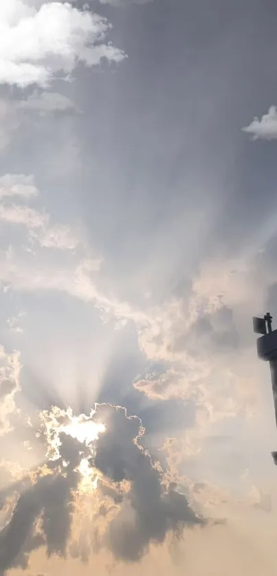 Sunlit clouds with a silhouetted streetlight in a serene sky.