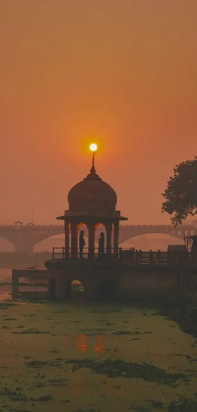 Sunset behind a riverside gazebo with orange hues and serene atmosphere.