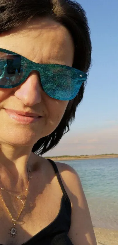 Woman wearing blue sunglasses on a sunny beach.