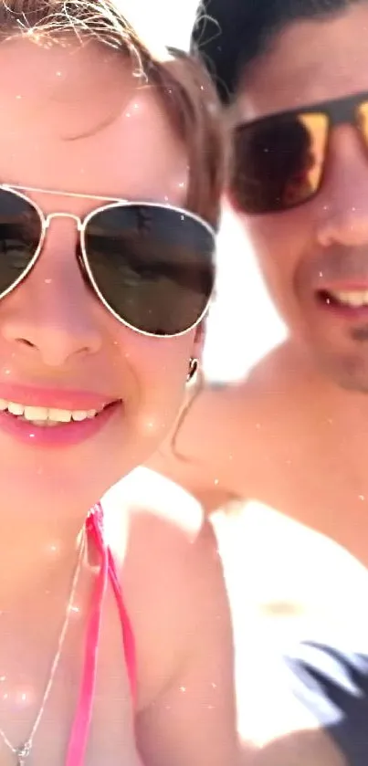 Happy couple capturing a sunny beach selfie with smiles in the warm sunshine.