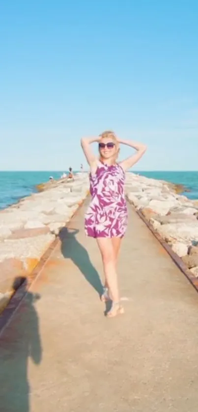 Woman walking on a sunny beach pathway with ocean in the background.