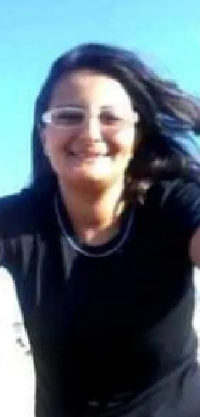 Woman smiling on a sunny beach with a blue sky.