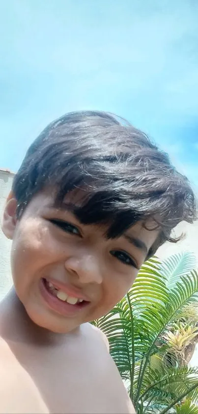 Cheerful child smiling in a sunny outdoor setting.