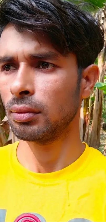 Portrait of person in a bright yellow shirt with a nature background.