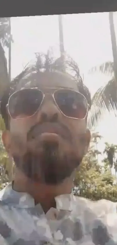 Man with sunglasses in tropical setting, sunlit background.