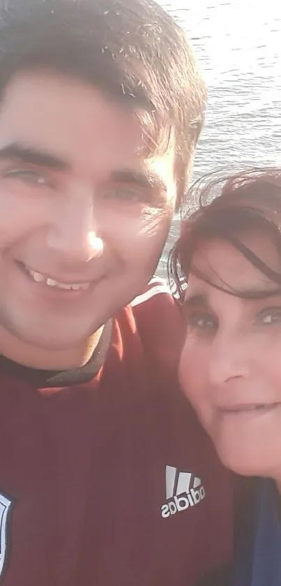 Couple taking a selfie by a sunny riverside, smiling with joy.