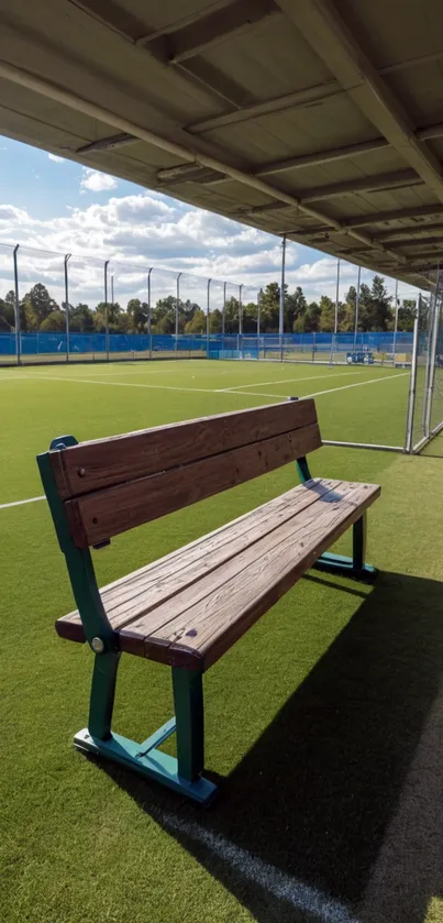 Sunny soccer field with wooden bench in the foreground.