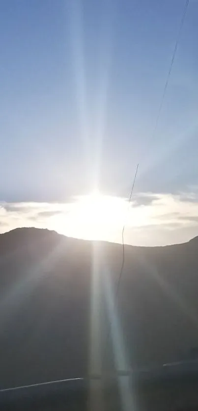 Beautiful sunrise over mountain peaks with radiant sunlight and clear blue sky.