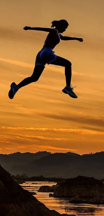 Silhouette jumping over rocks with a sunset background.