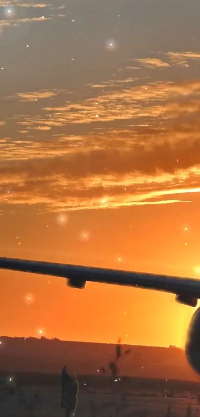Airplane silhouette against an orange sunset sky.