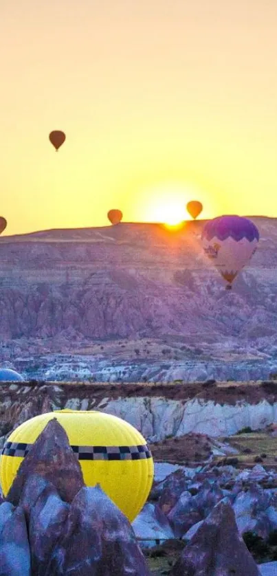 Hot air balloons at sunset over rocky landscape.