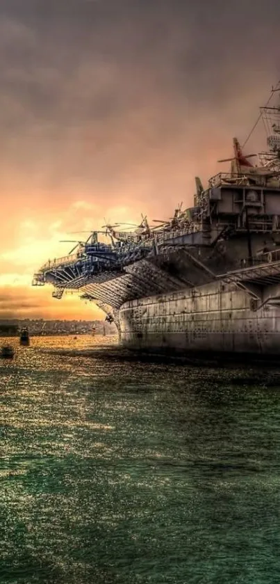 Battleship silhouetted against a warm sunset over the ocean.