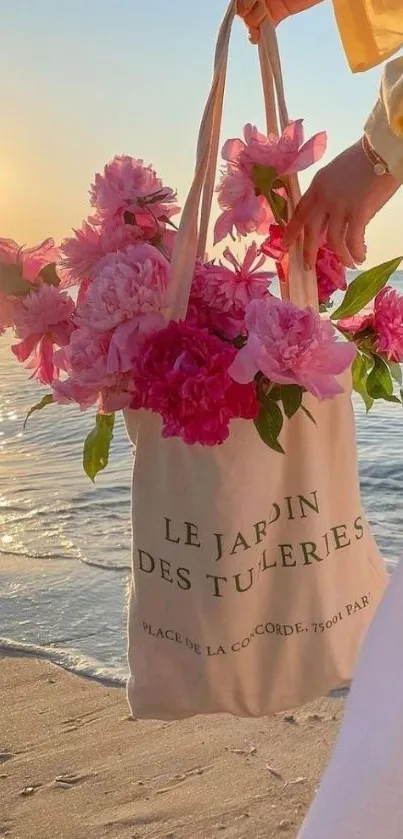 Tote bag with pink flowers on a beach at sunset.