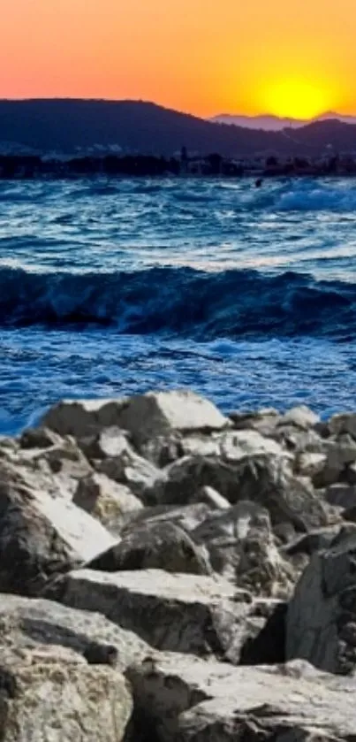 Sunset over ocean waves and rocky beach landscape.