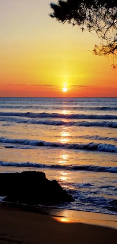 A serene sunset over ocean waves with a silhouette of a tree on the beach.