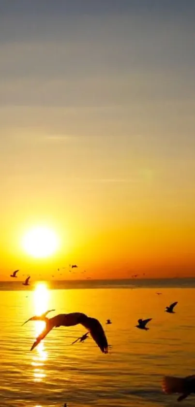 Golden sunset with flying birds over the ocean.