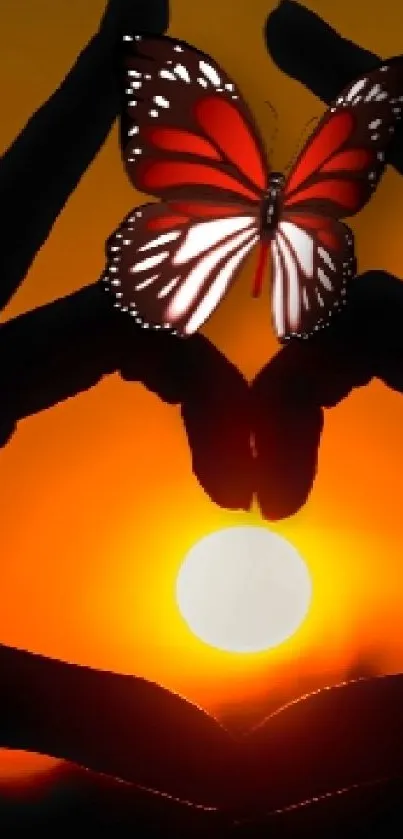 Silhouette of hands with butterfly at sunset, orange background.