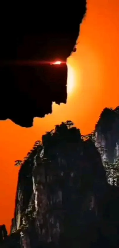 Silhouette of a cliff against an orange sunset, creating a dramatic visual effect.