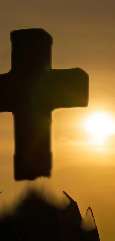 Silhouette of a cross at sunset with golden sky background.