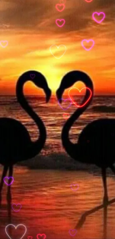 Two flamingos silhouetted against an orange sunset by the ocean.