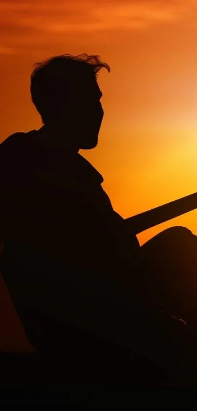 Silhouette of a guitarist at sunset with vibrant orange sky.