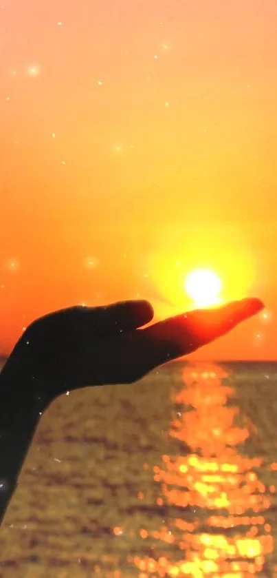 Hand holding the sun at sunset over ocean with sparkling reflections.