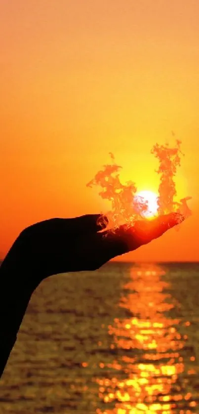 Hand silhouette holding setting sun over ocean at sunset.