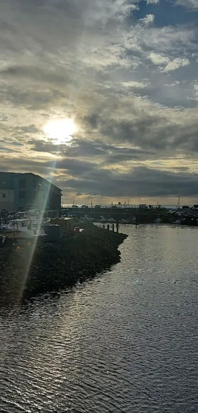 Tranquil sunset view over a harbor with reflective water and cloudy skies.