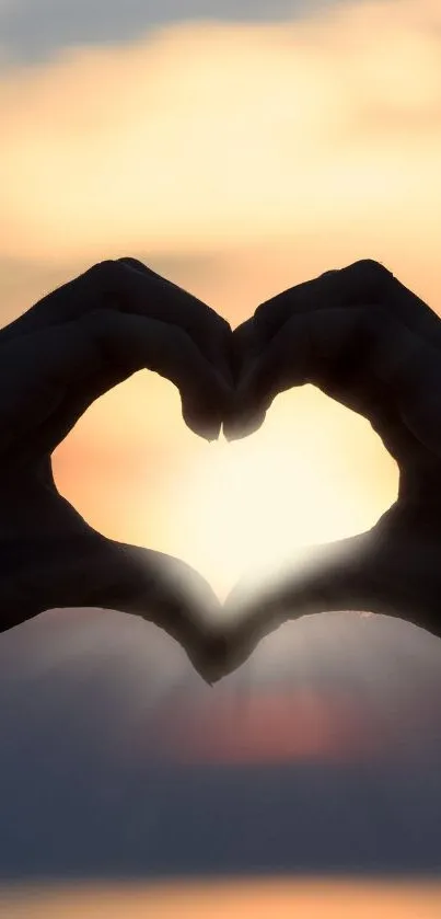 Heart-shaped hands silhouette at sunset.