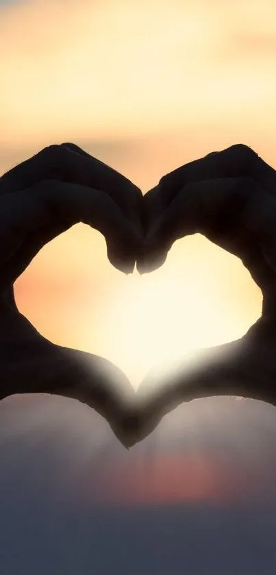 Silhouette hands forming heart with sunset backdrop.