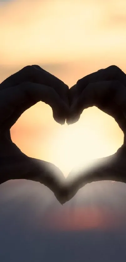 Silhouette of hands in heart shape against sunset.