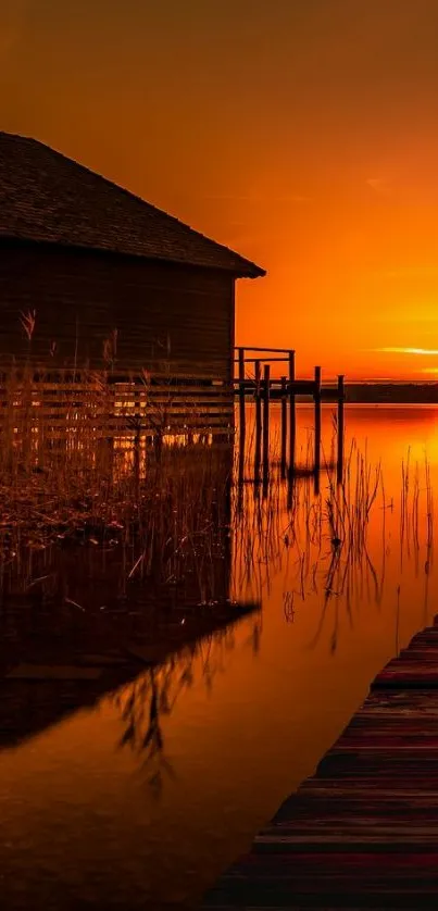 Orange sunset over a serene lake with house reflection.