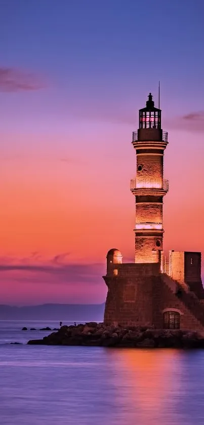 Lighthouse at sunset with orange and violet sky over the ocean.