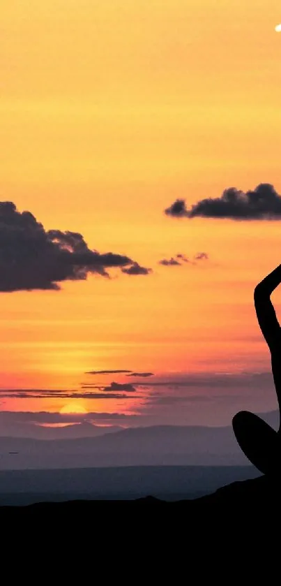 Silhouette meditating at sunset with orange sky background.