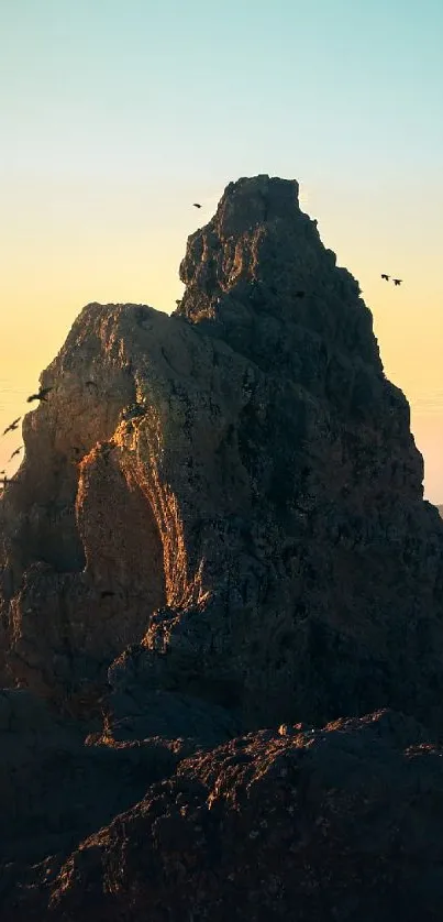 Mountain peak at sunset with birds flying in the sky, ideal mobile wallpaper.