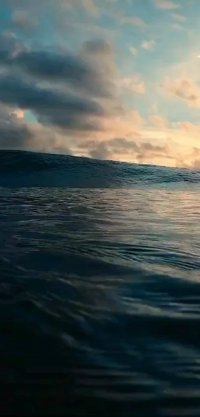 Peaceful sunset over ocean waves with a cloudy sky.