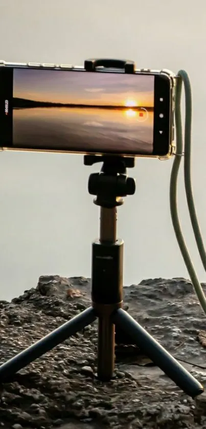 Smartphone capturing a stunning sunset on a tripod by the lake.