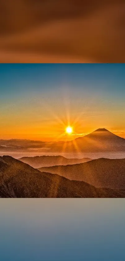 Sunset over mountain peaks with vibrant orange hue and clear sky.