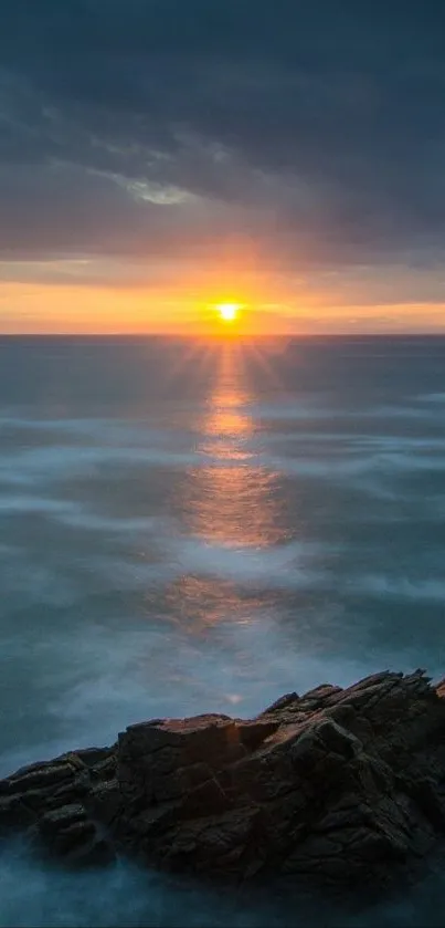 Beautiful sunset over the ocean with a rocky shore in the foreground.