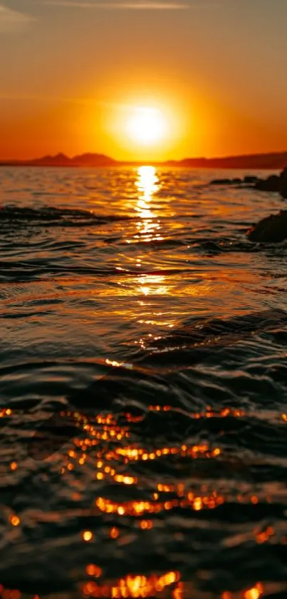 Stunning orange sunset over ocean waves, reflecting golden hues.