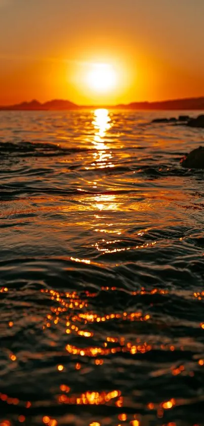 Vibrant sunset over ocean waves, reflecting orange hues in serene waters.