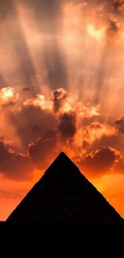 Pyramid silhouette with sunset rays casting dramatic sky shadows.