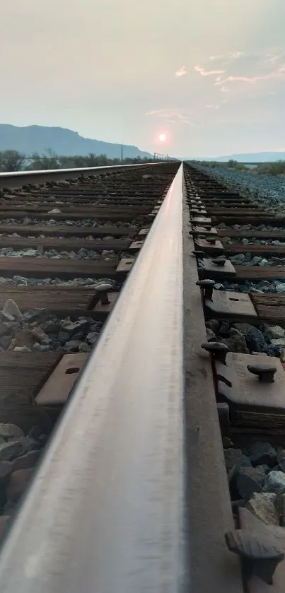 Sunset over railway tracks with serene landscape.