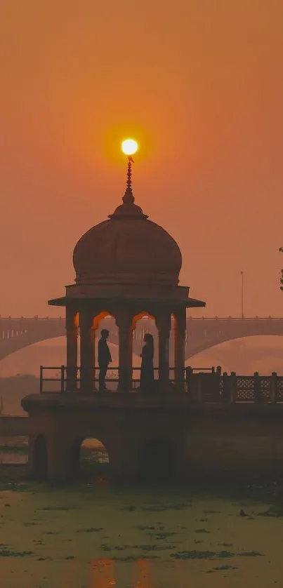 Sunset behind a pavilion by the river with an orange sky.