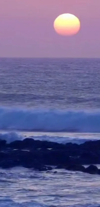 Sunset over the ocean with calming waves and a purple sky.