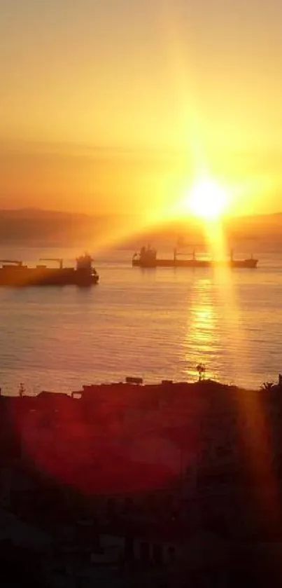 Golden sunset over ocean with ships reflecting on tranquil waters.