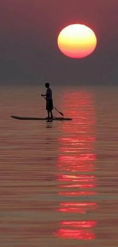 A solitary paddleboarder under a vibrant sunset on calm waters.