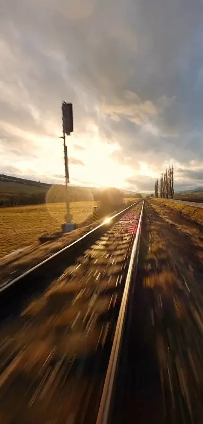 Sunset over railway tracks with fields and clouds.